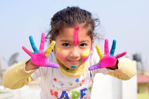 Happy child with paint on hands and face.