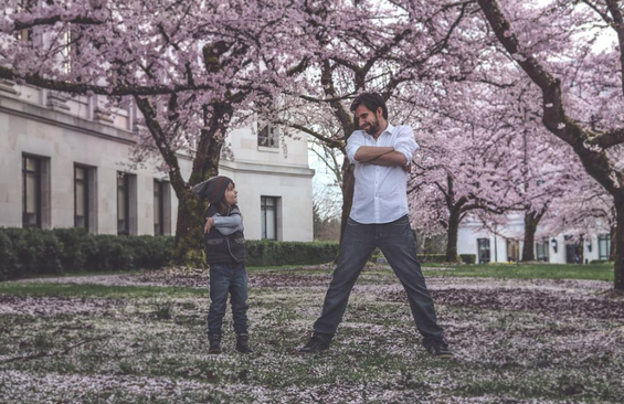 Father and son smiling at each other near blooming trees.