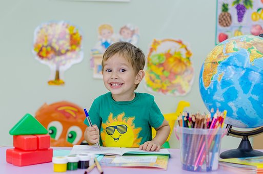 Picture of young child smiling with colored pencils.