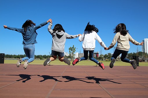 Picture of adolescents jumping in the air while holding hands.